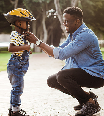 Father putting helmet on son